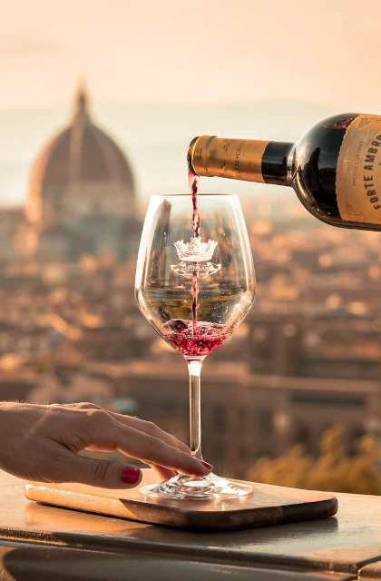 Wein fließt in ein Weinglas. Italien im Hintergrund.